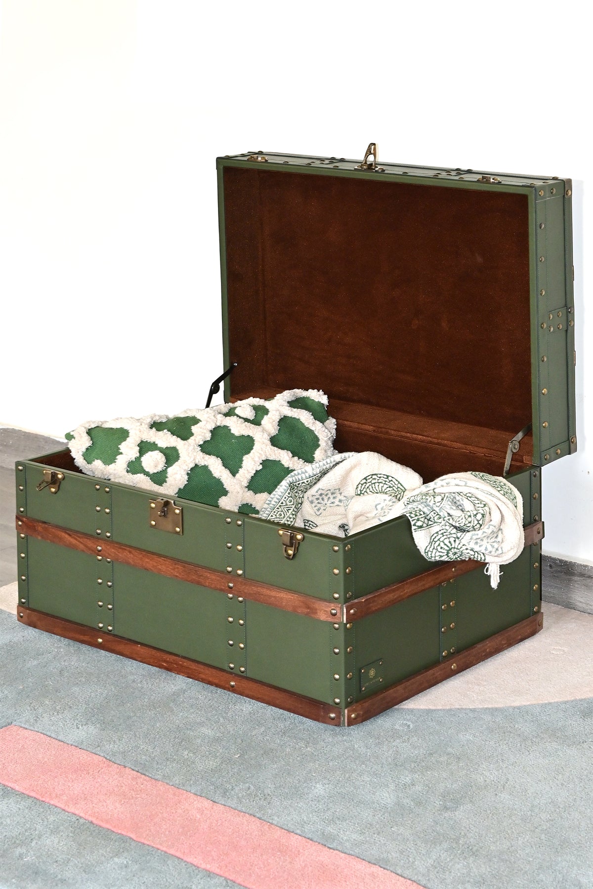 Open leather trunk used as blanket storage, holding a cushion and throw — Art Avenue