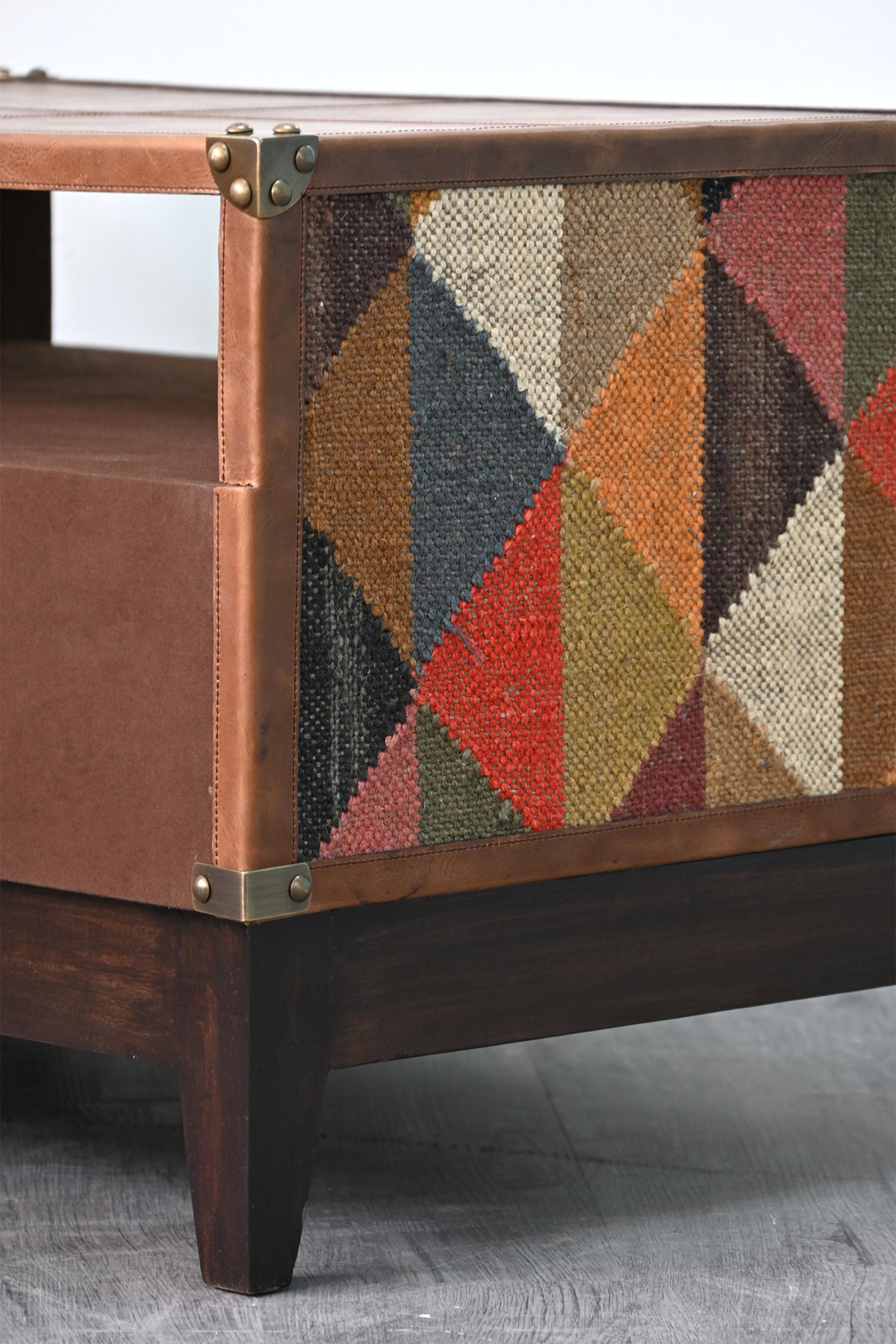 Macro detail of the vintage kilim weave and brass corner cap on the Barmer TV unit