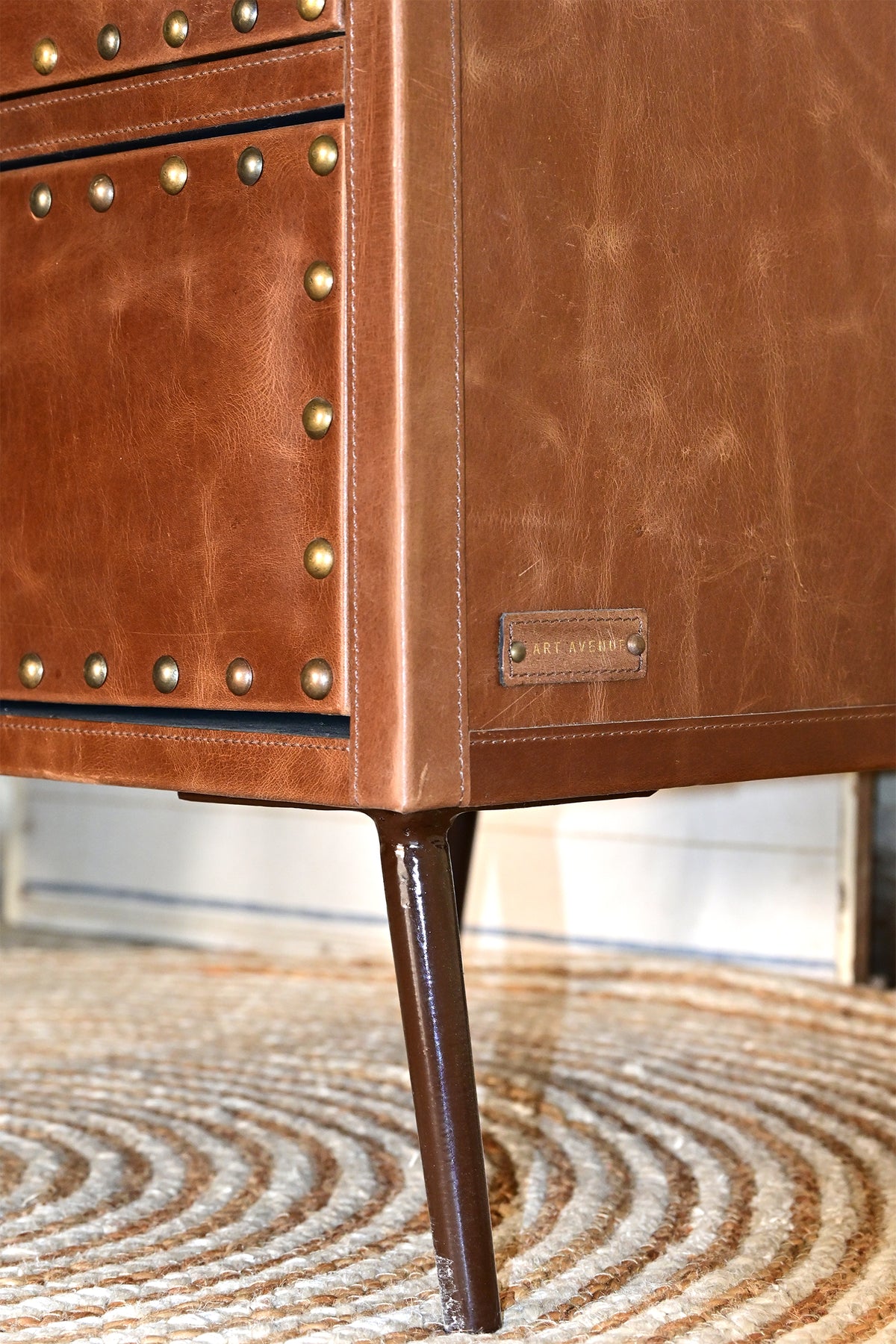Detail of Art Avenue leather maker's tag and tapered metal leg, Kishangarh bedside table