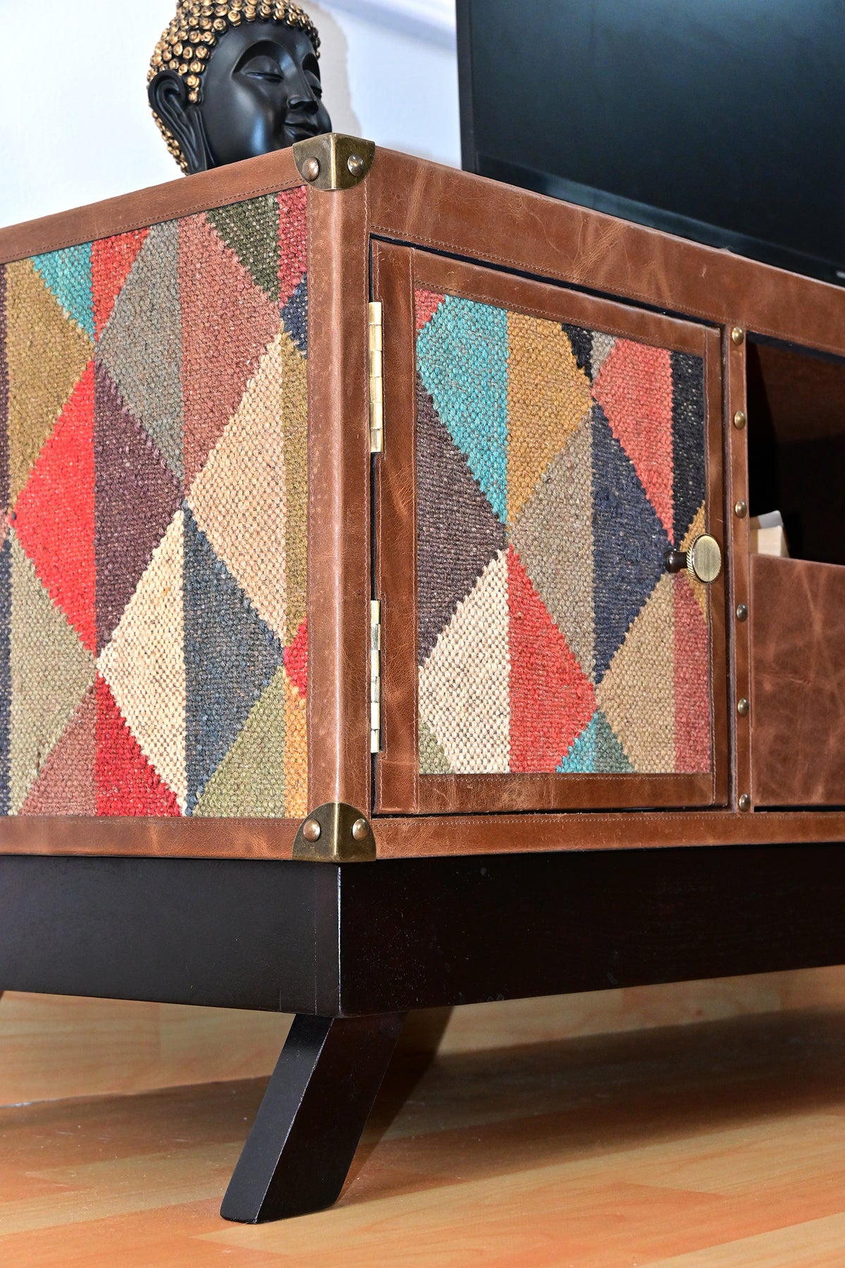 Close-up of the kilim flank and door framed in leather with brass corner caps and hinges