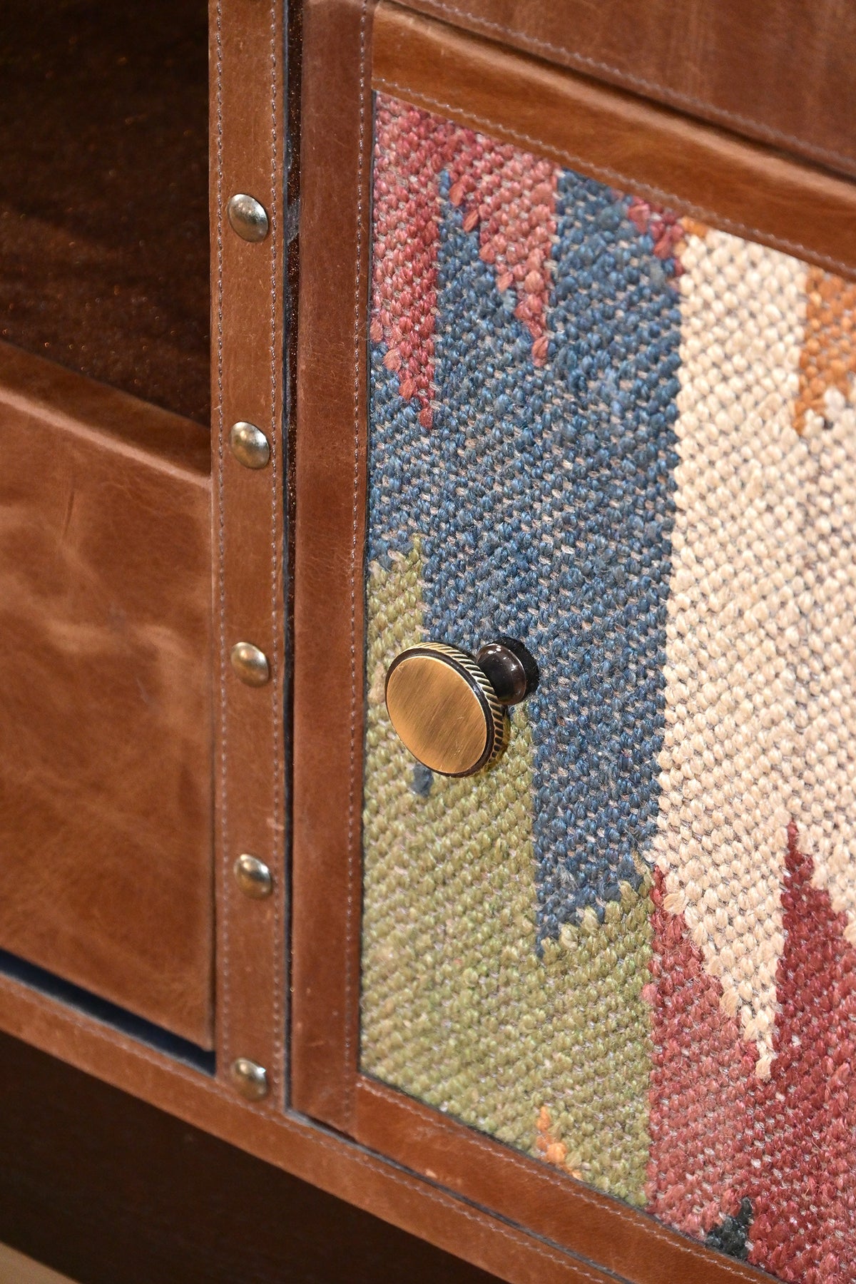 Detail of the knurled brass knob on a kilim door beside the studded leather rail