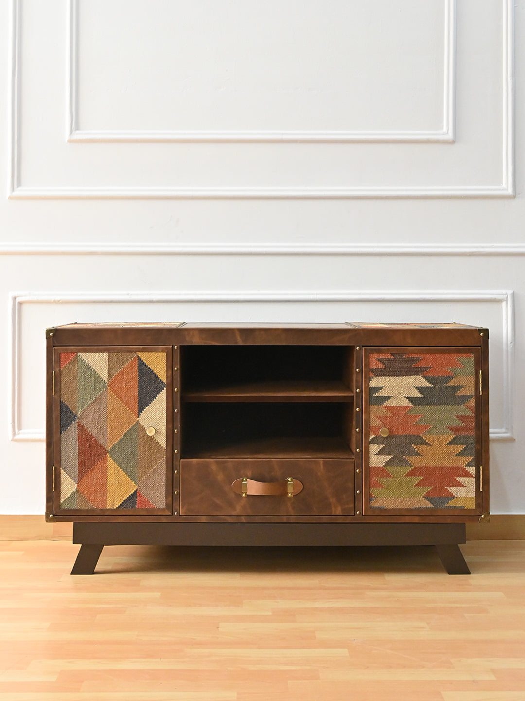 Mukundgarh kilim and leather TV unit, front view — two kilim-panelled doors, two open compartments and a strap-handled drawer on splayed solid wood legs