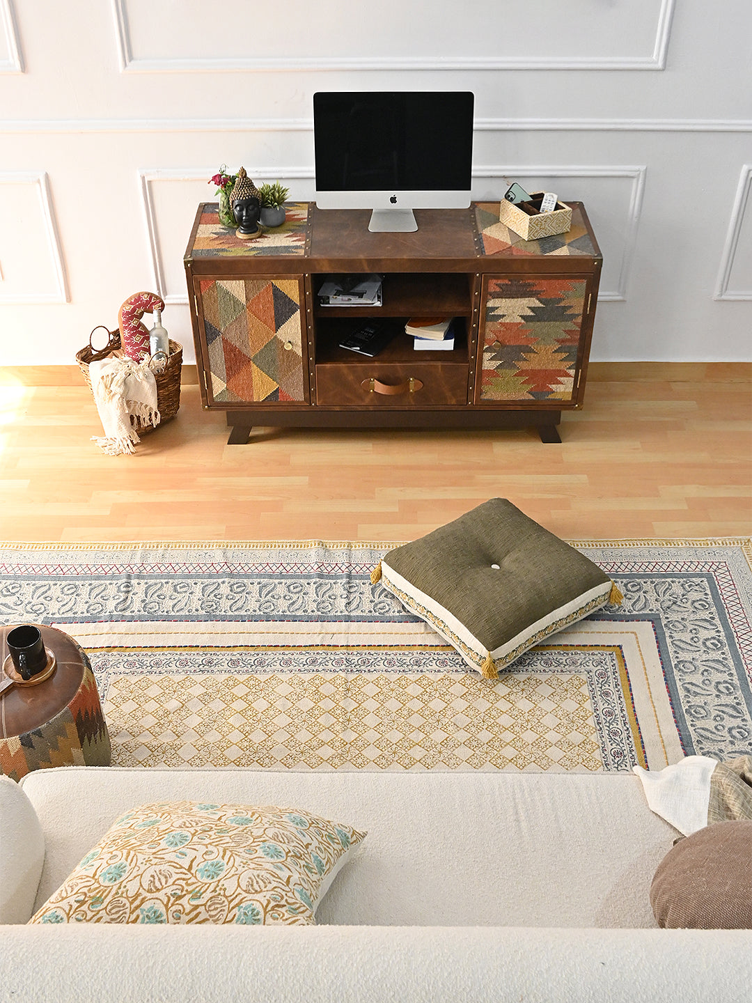 Overhead view across a living room to the Mukundgarh kilim and leather TV unit, with a block-printed rug and floor cushion in front
