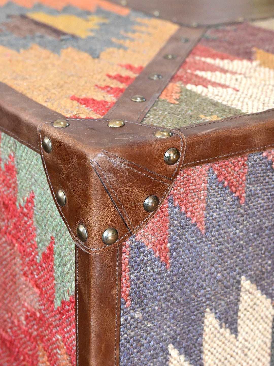 Detail of the stitched leather corner cap and hand-hammered domed studs on the Mandawa kilim coffee table