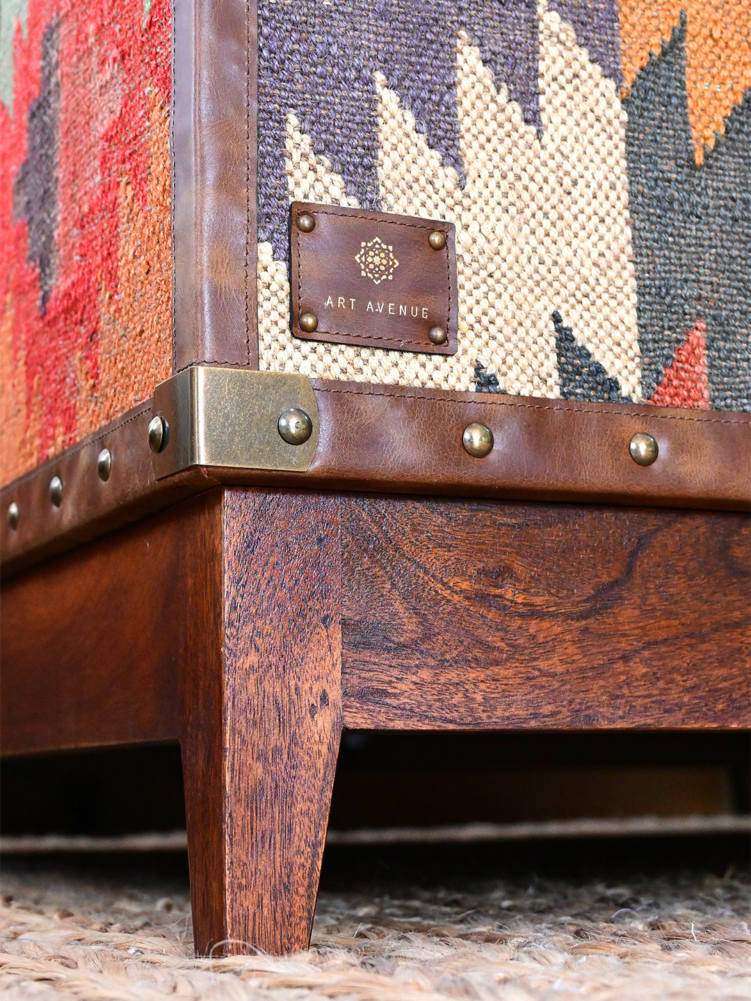 Detail of the Art Avenue maker's tag, brass corner plate and tapered wood leg, Mandawa kilim coffee table