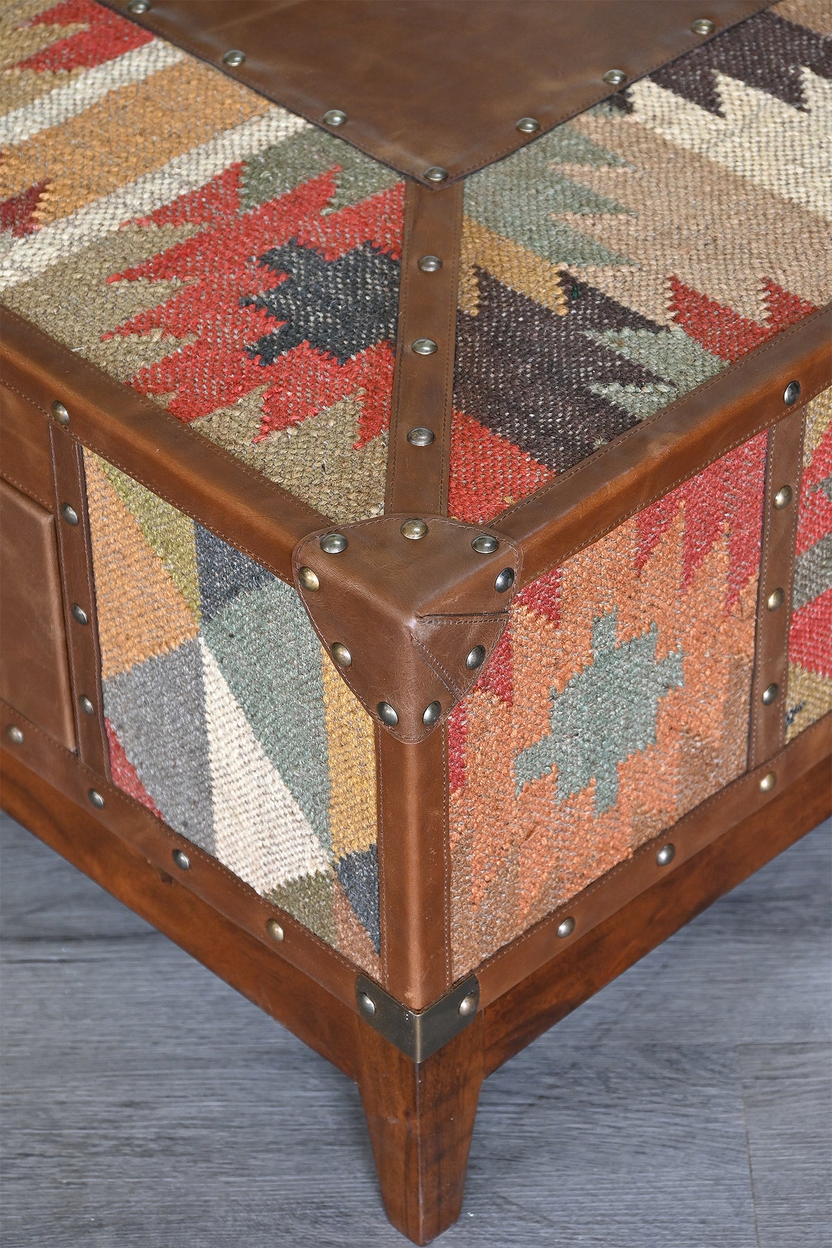Close detail of leather binding, domed studs and mitred corner cap on the kilim top