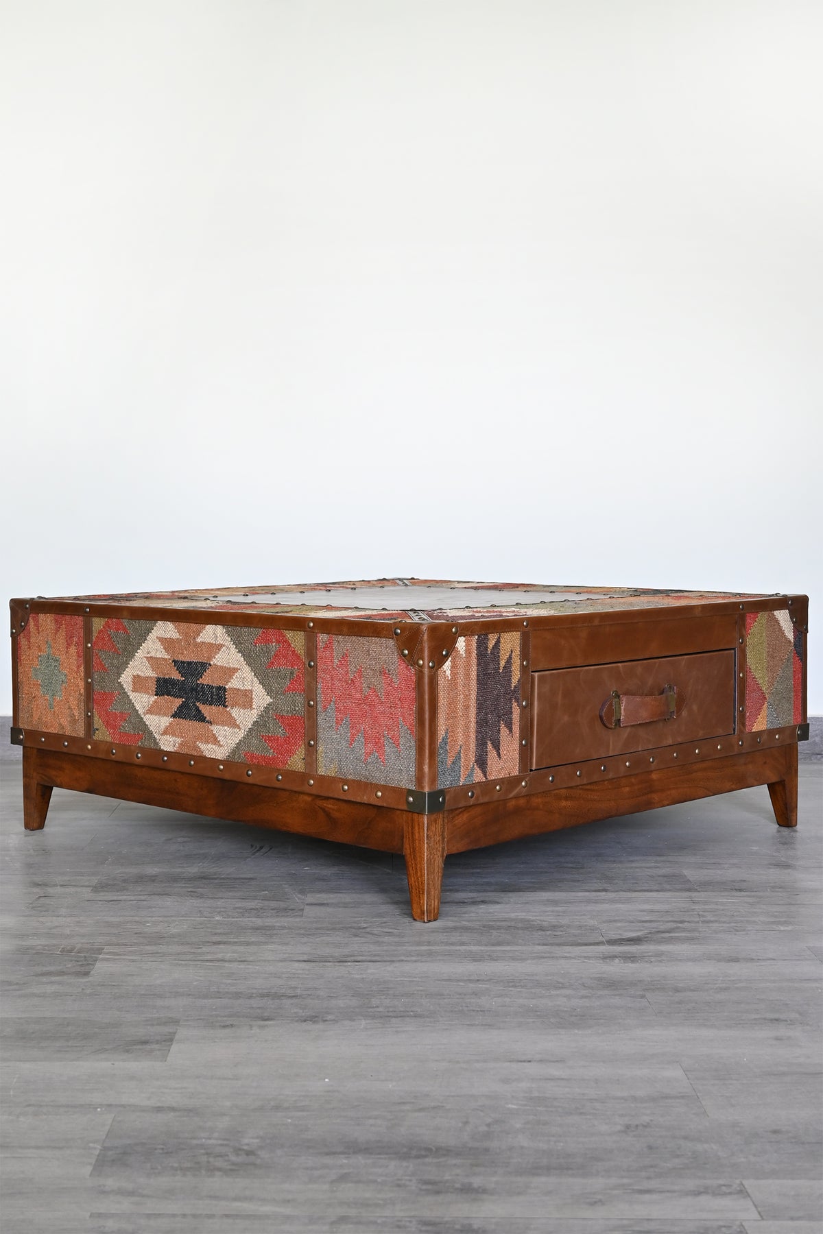 Angled view of the Mandawa kilim coffee table showing the leather drawer front