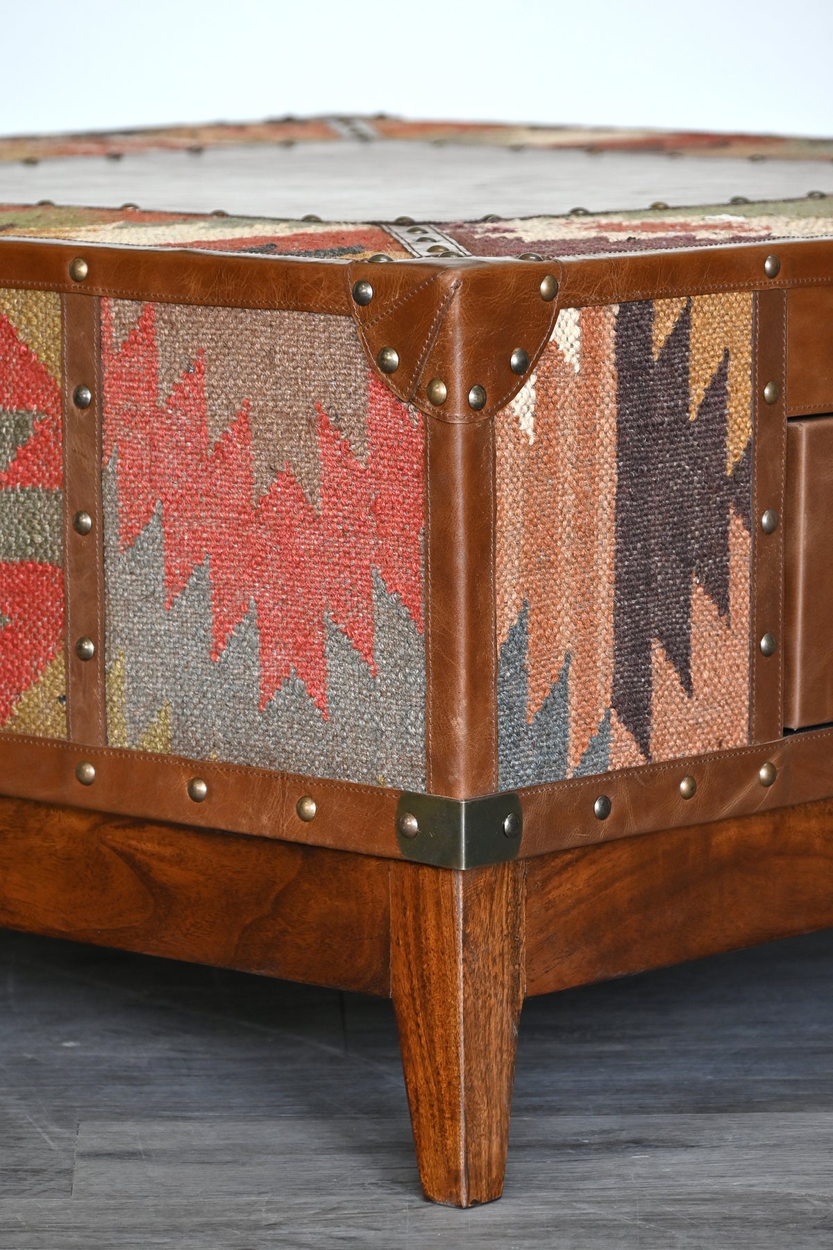 Detail of the studded leather corner cap, brass bracket and tapered mango wood leg
