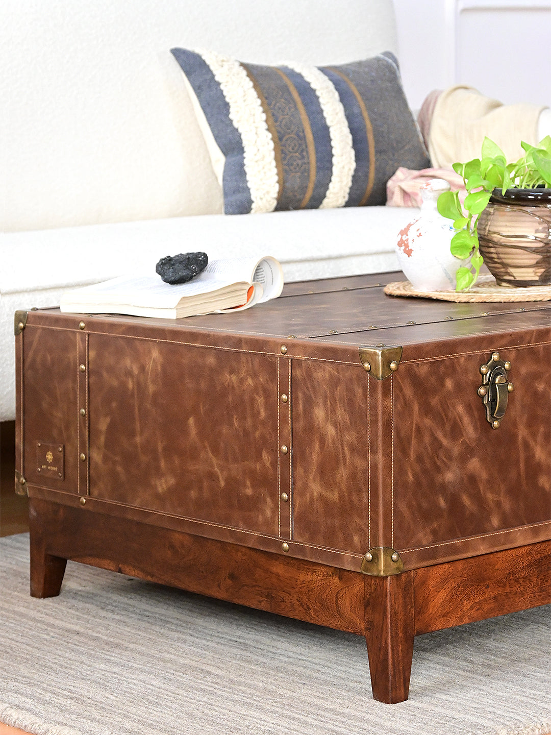 Nawalgarh leather trunk coffee table, three-quarter view of the studded end panel, corner caps and maker's tag