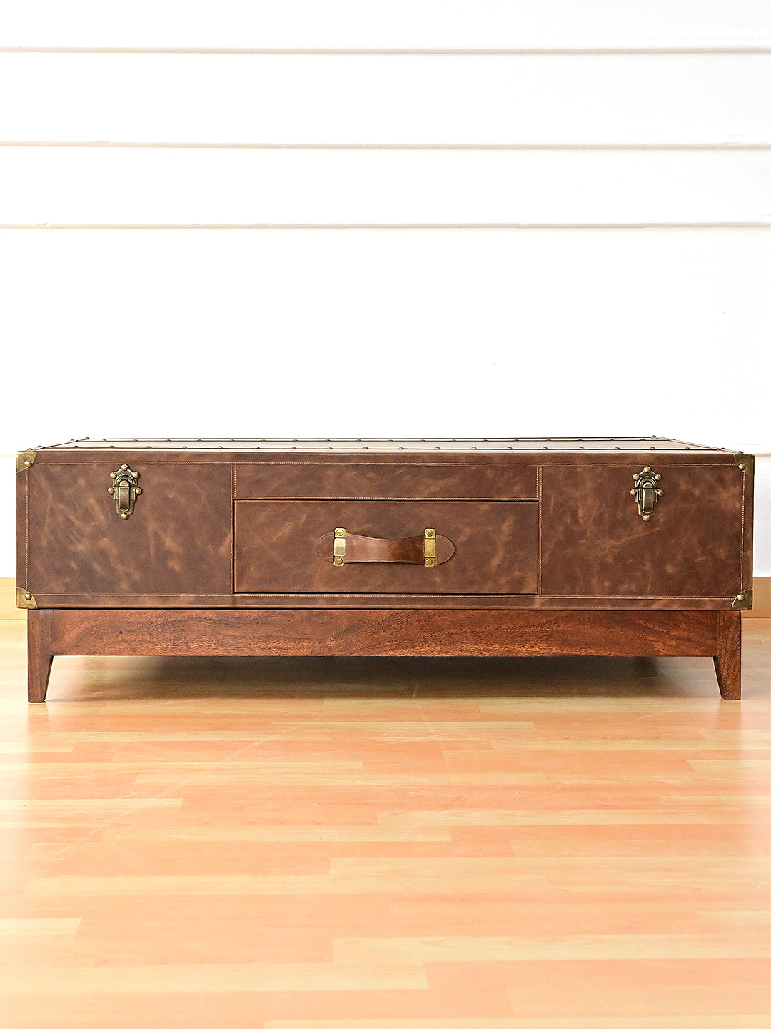 Nawalgarh leather trunk coffee table, front view: drawer between two trunk catches on a solid wood plinth