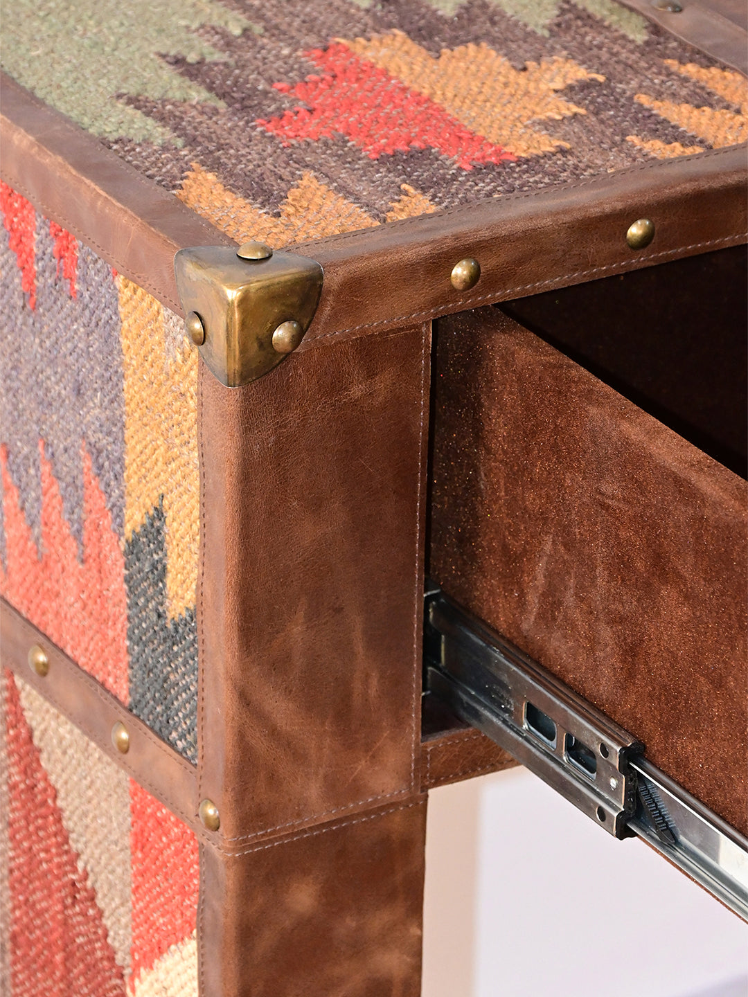 Brass corner cap and studded leather edge above an open drawer on its runner