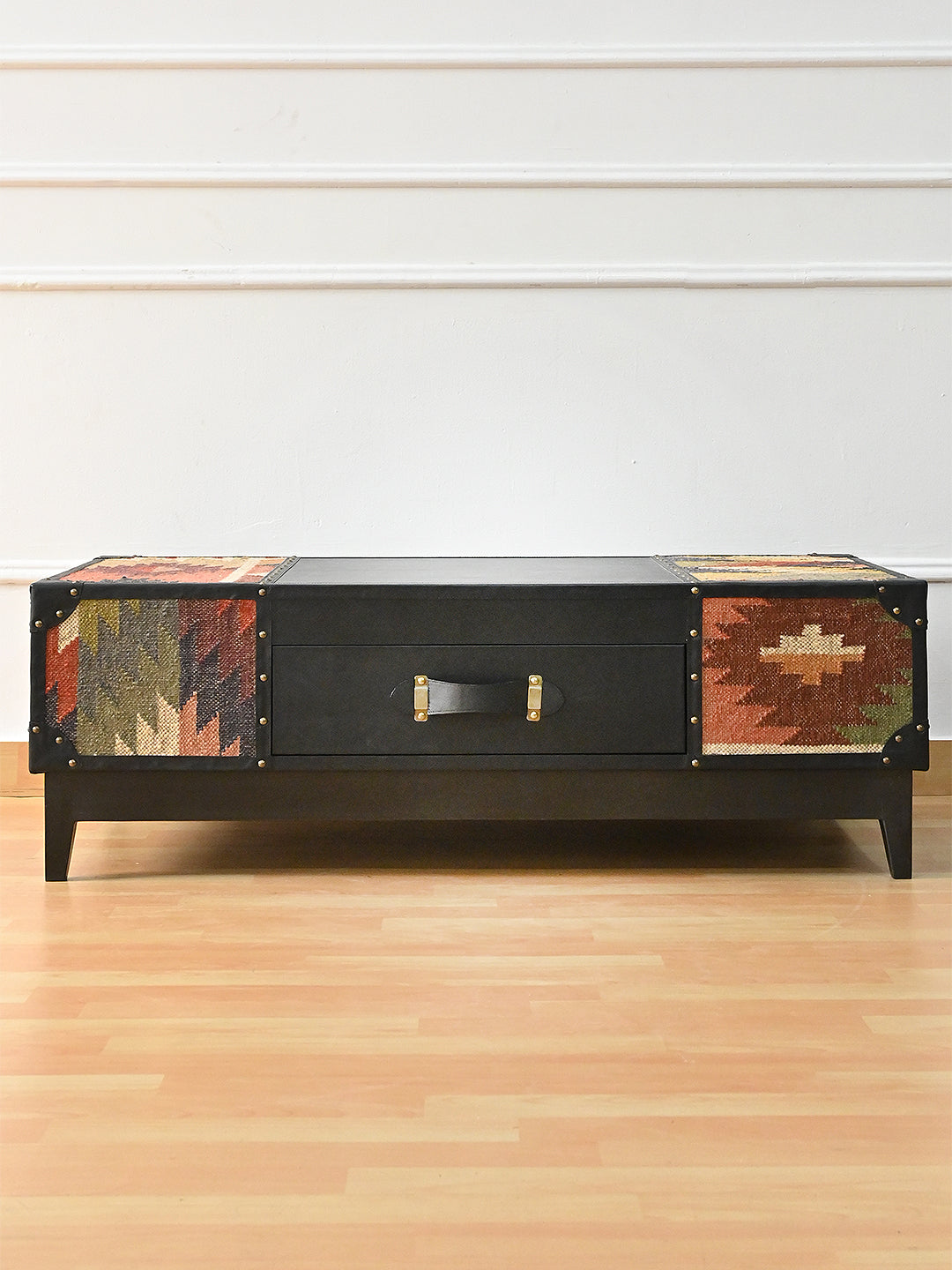 Kumbhalgarh coffee table, front view — black leather drawer between vintage kilim panels, on a black solid wood plinth with tapered legs