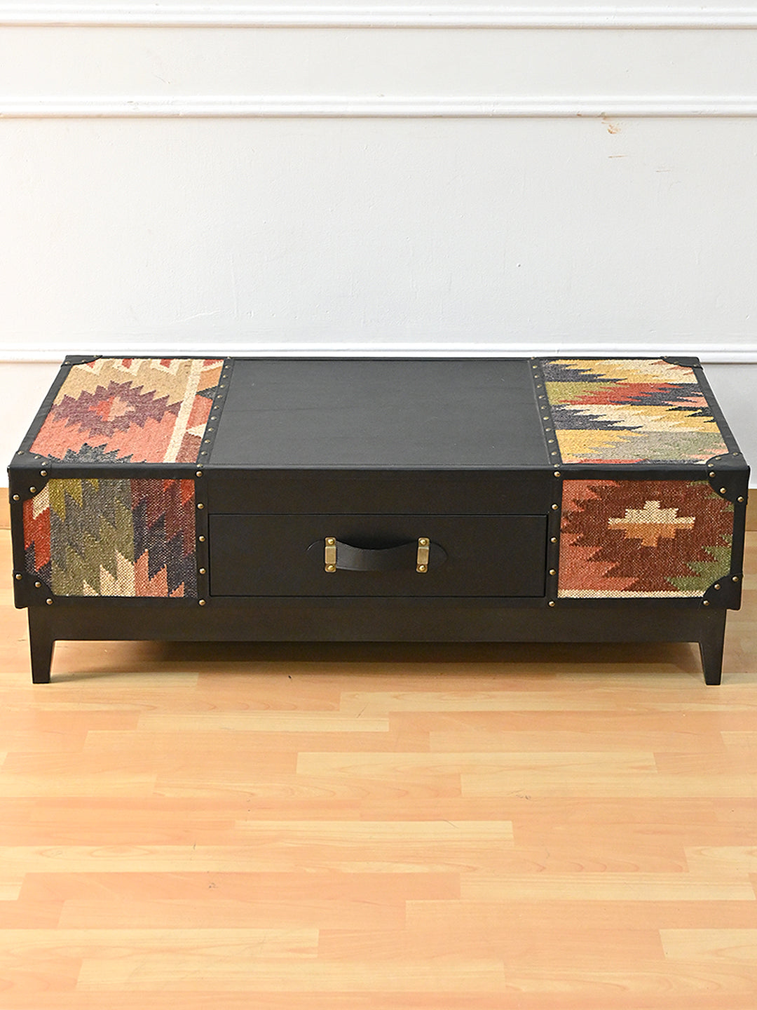 Kumbhalgarh kilim and black leather coffee table seen from a raised front angle