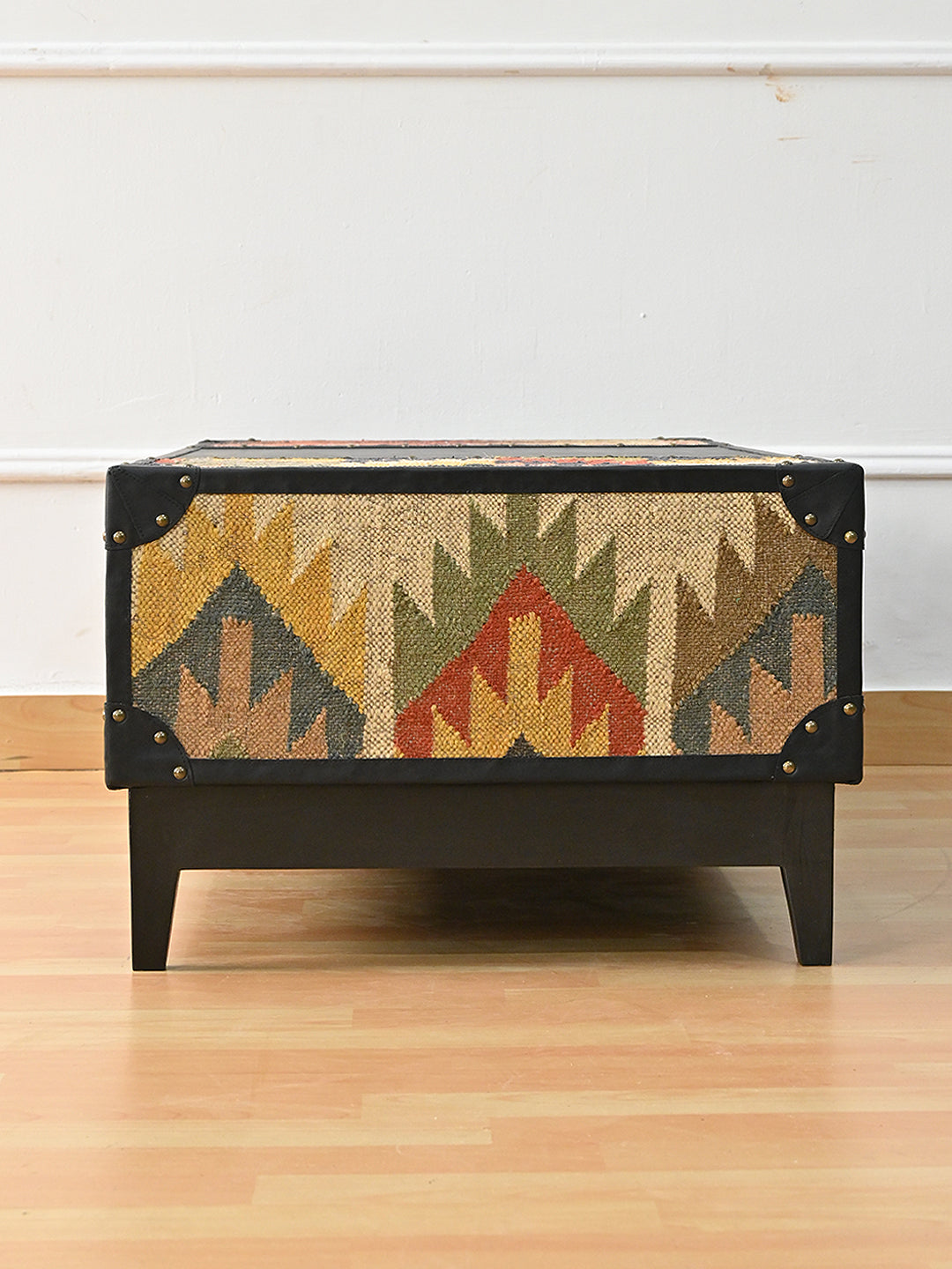 Short end of the Kumbhalgarh coffee table — full kilim panel framed in black leather with studded corner caps