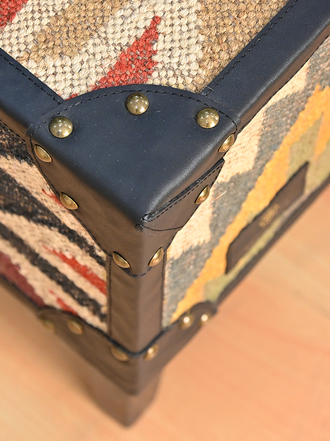 Detail of a shaped black leather corner cap set with hand-hammered brass domed studs