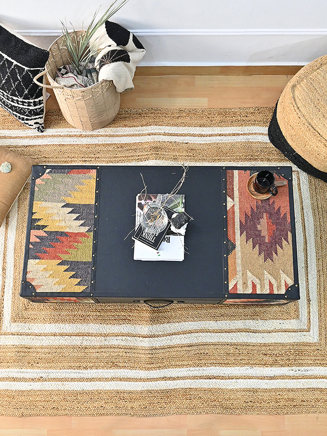 Top view of the Kumbhalgarh coffee table on a jute rug with books and a vase on the black leather centre