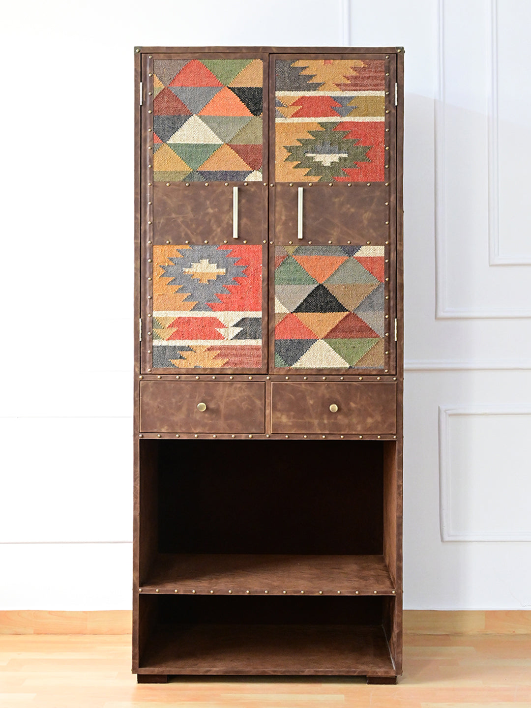 Front view of the Alsisar kilim and leather wardrobe with brass bar pulls, two drawers and open lower bay