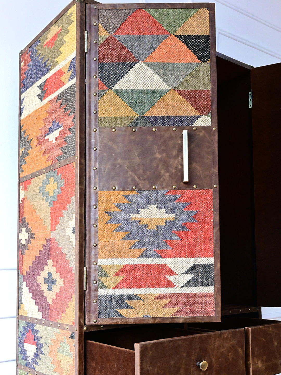 Close view of an Alsisar wardrobe door: kilim bands, leather centre panel, brass pull and domed studs