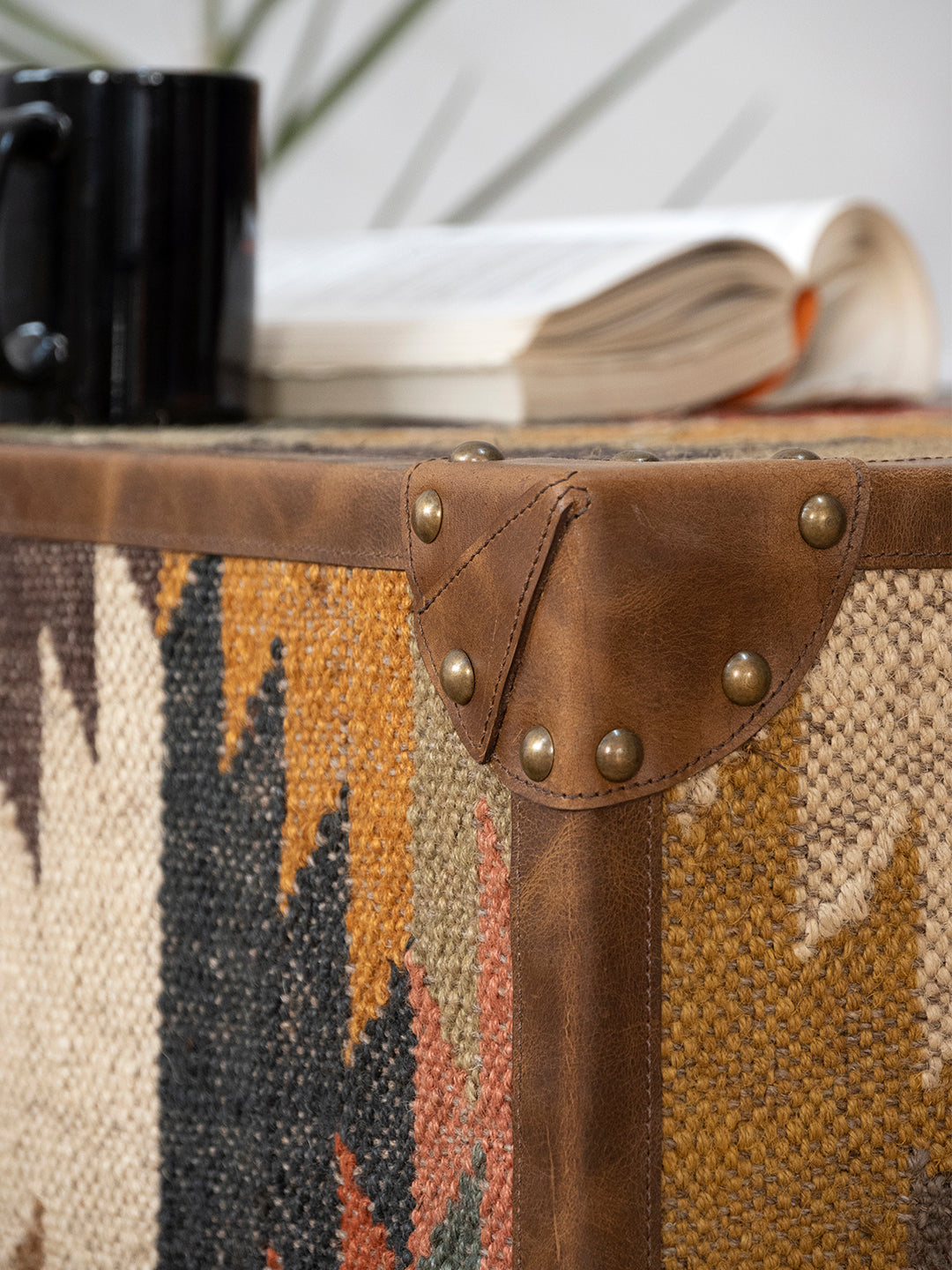 Close-up of a stitched leather corner cap with domed studs on the Sojat kilim coffee table, by Art Avenue