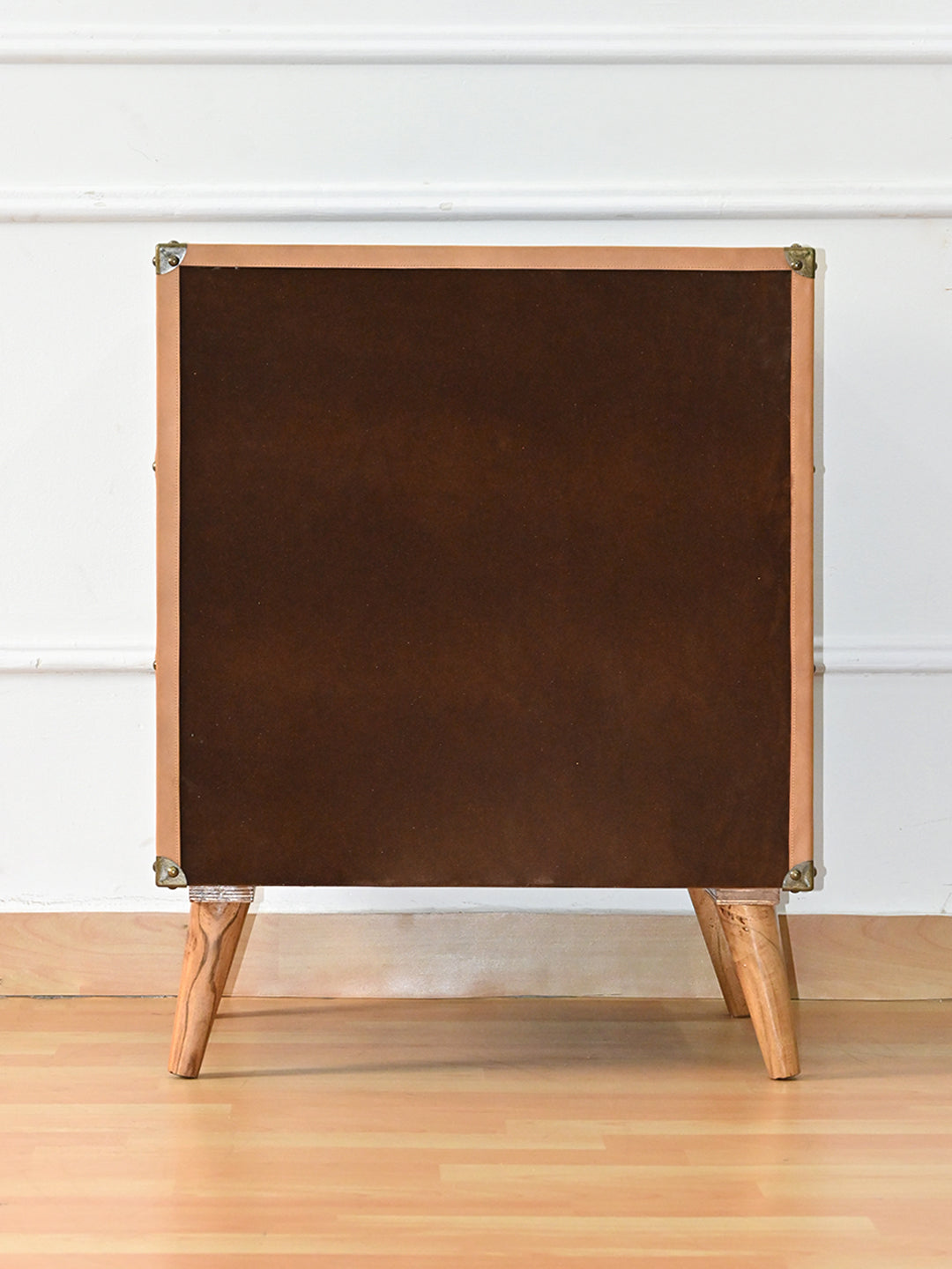 Back of the Sariska chest of drawers, faced in brown suede finish and bound in tan leather with metal corner caps