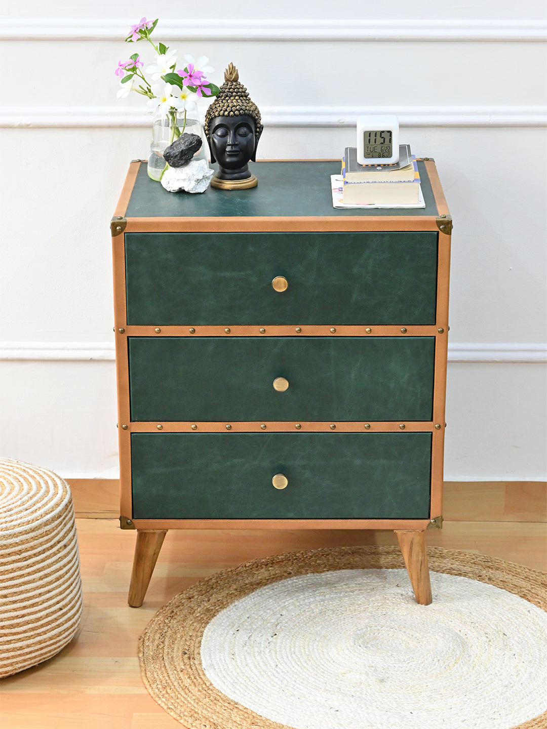 Sariska green leather chest of drawers with decor on top, beside a jute pouf and round rug