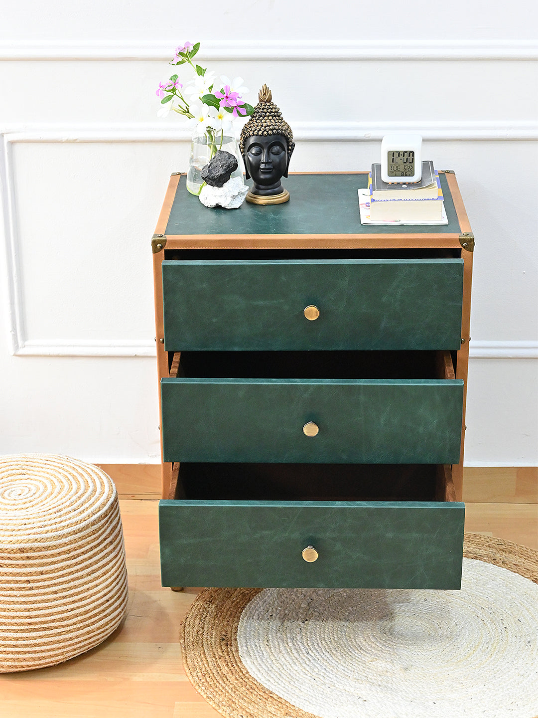 Styled Sariska chest of drawers with its three drawers open, a Buddha head and orchids on the leather top