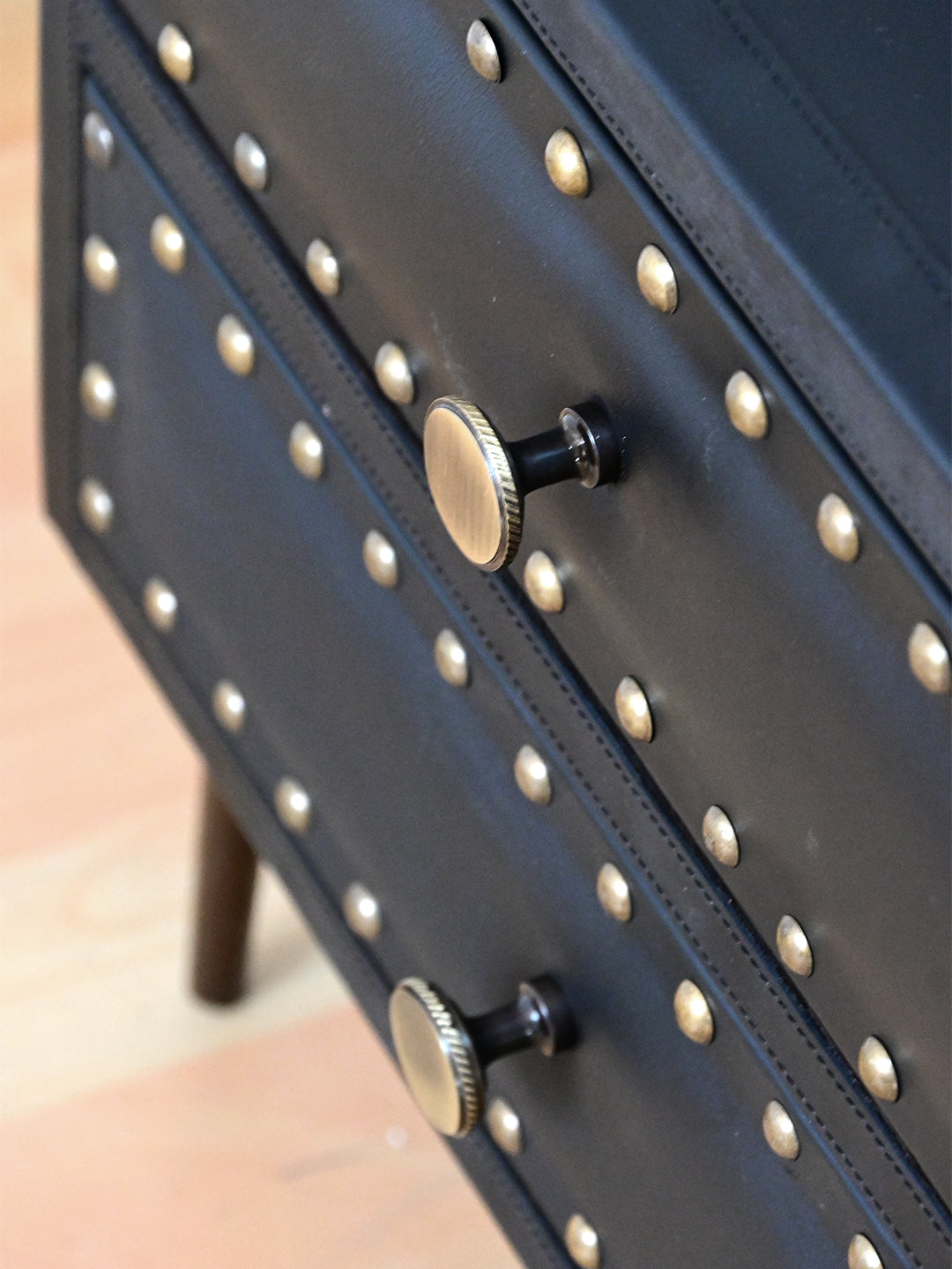 Detail of knurled brass knobs and hand-set studs on Onyx leather drawer fronts, Kishangarh bedside table