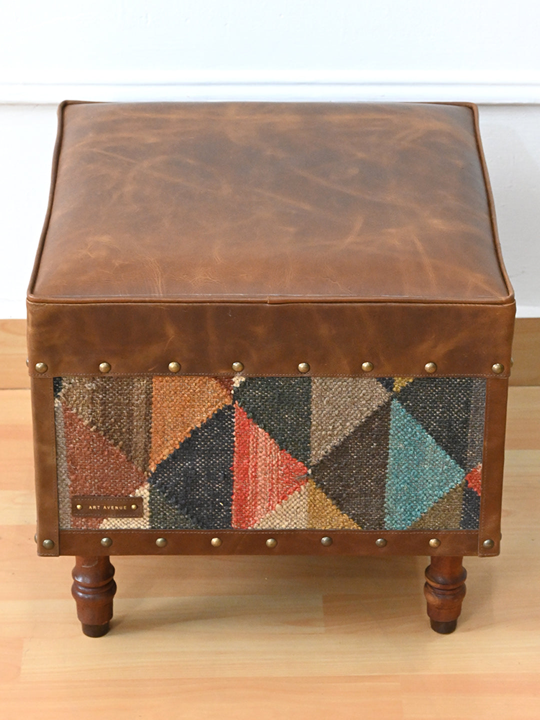 Top view of the Dundlod ottoman's padded leather seat by Art Avenue, showing natural tonal variation in the hide