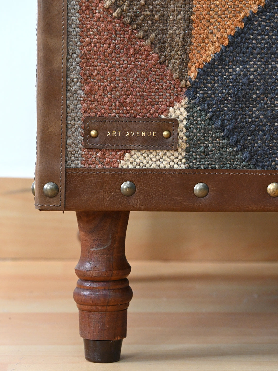 Stitched Art Avenue leather maker's tag and turned solid wood leg on the Dundlod kilim ottoman