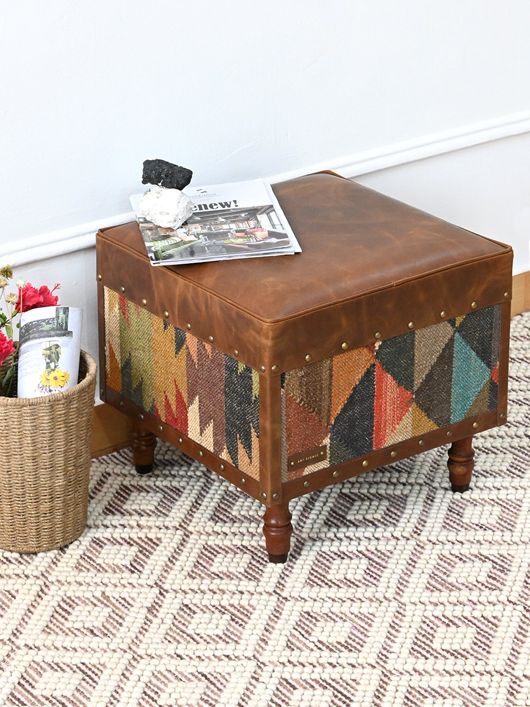 Dundlod ottoman by Art Avenue styled on a woven rug with magazines, handwoven kilim sides and padded leather seat
