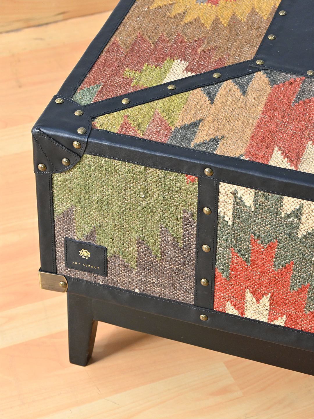 Top edge and corner of the Mehrangarh coffee table, Onyx leather binding over vintage kilim with the Art Avenue badge