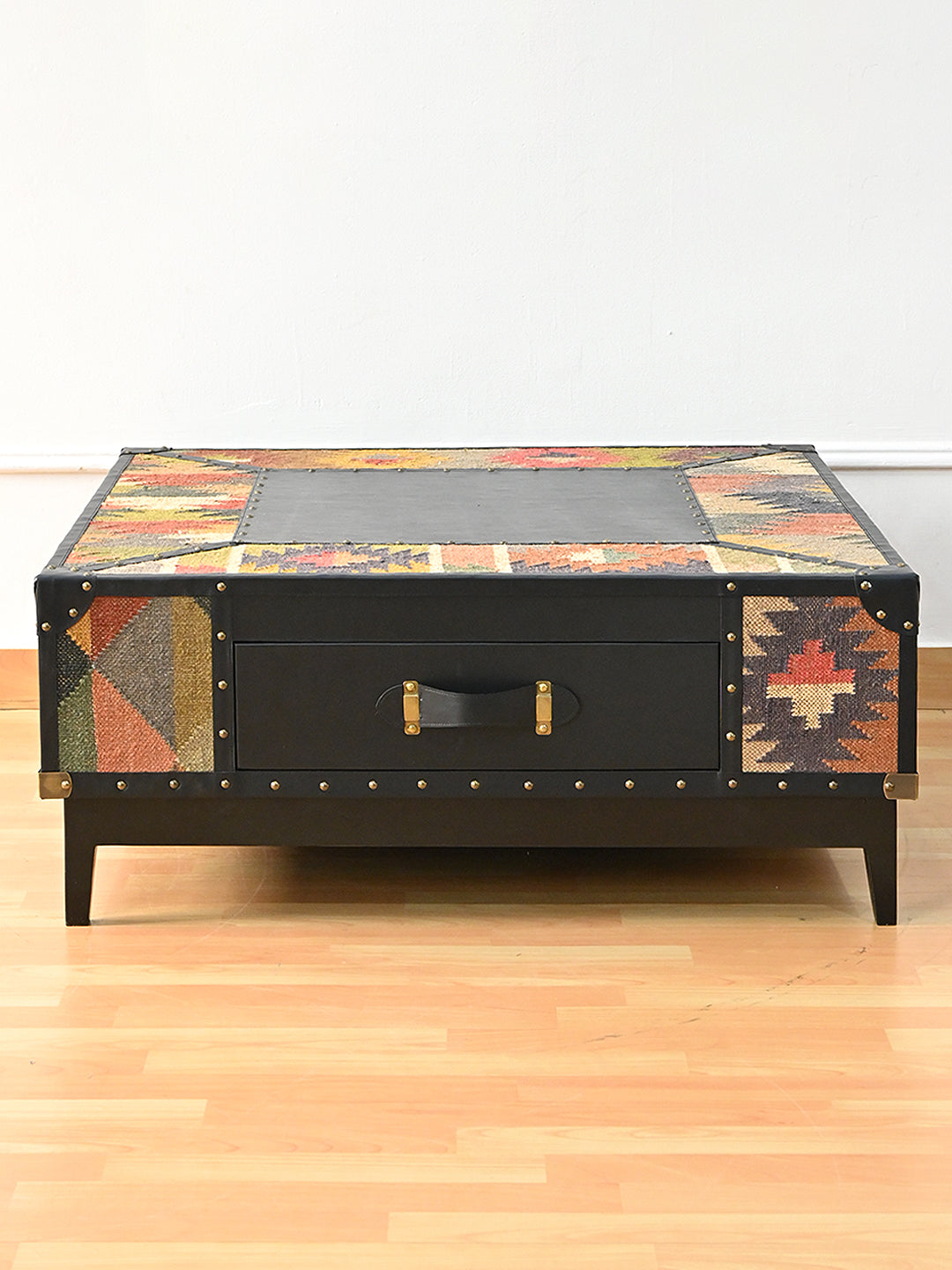 Drawer face of the Mehrangarh coffee table, plain Onyx leather front with a brass-mounted strap handle between kilim panels, Art Avenue