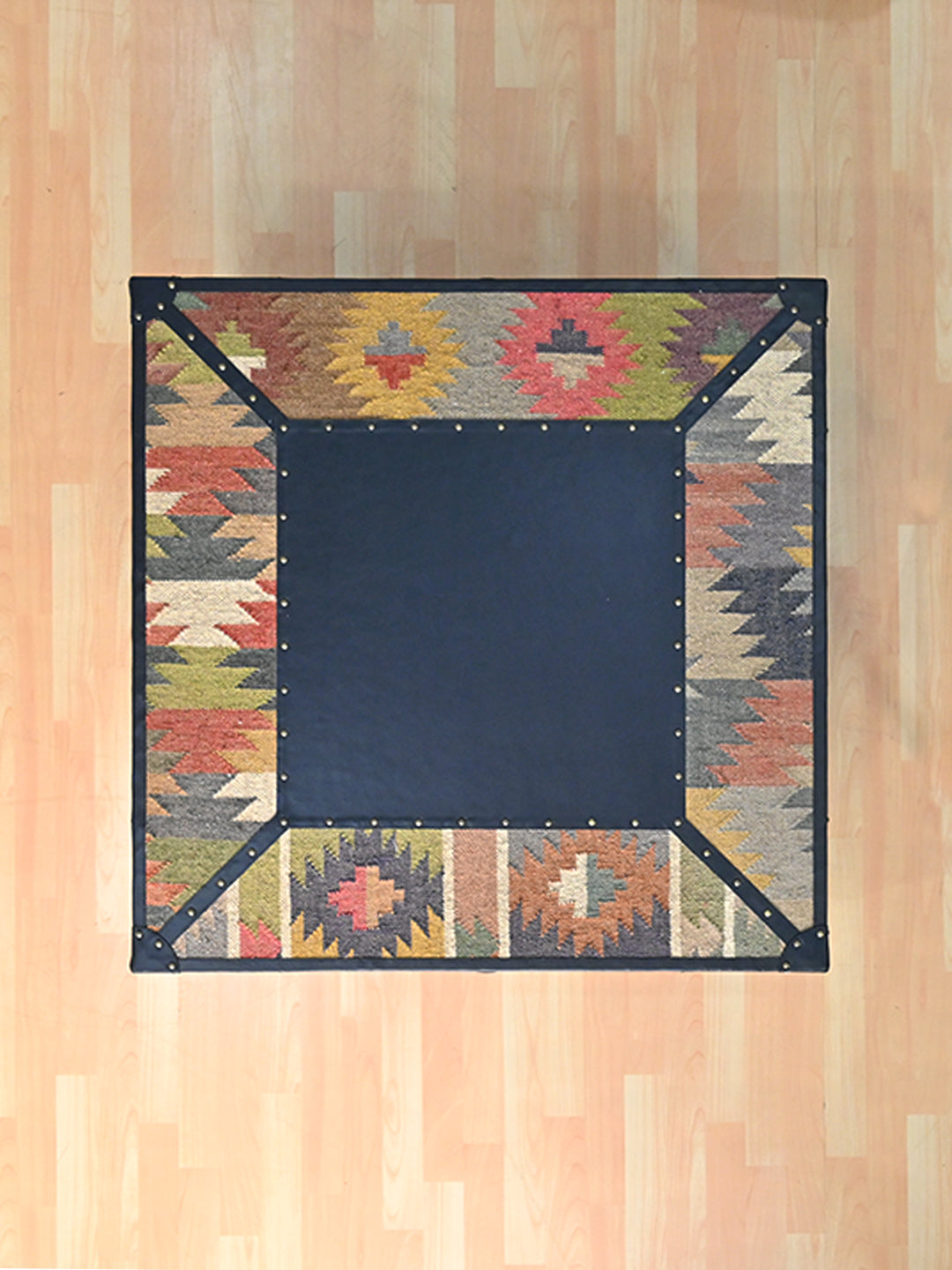 Overhead view of the Mehrangarh coffee table, square black leather field inside a mitred kilim border, Art Avenue