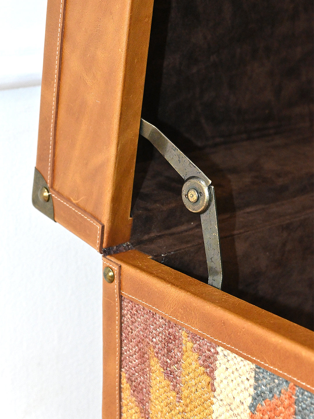 Brass stay arm and hinge inside the raised lid of the Osian trunk, showing the suede lining. Art Avenue, made to order.
