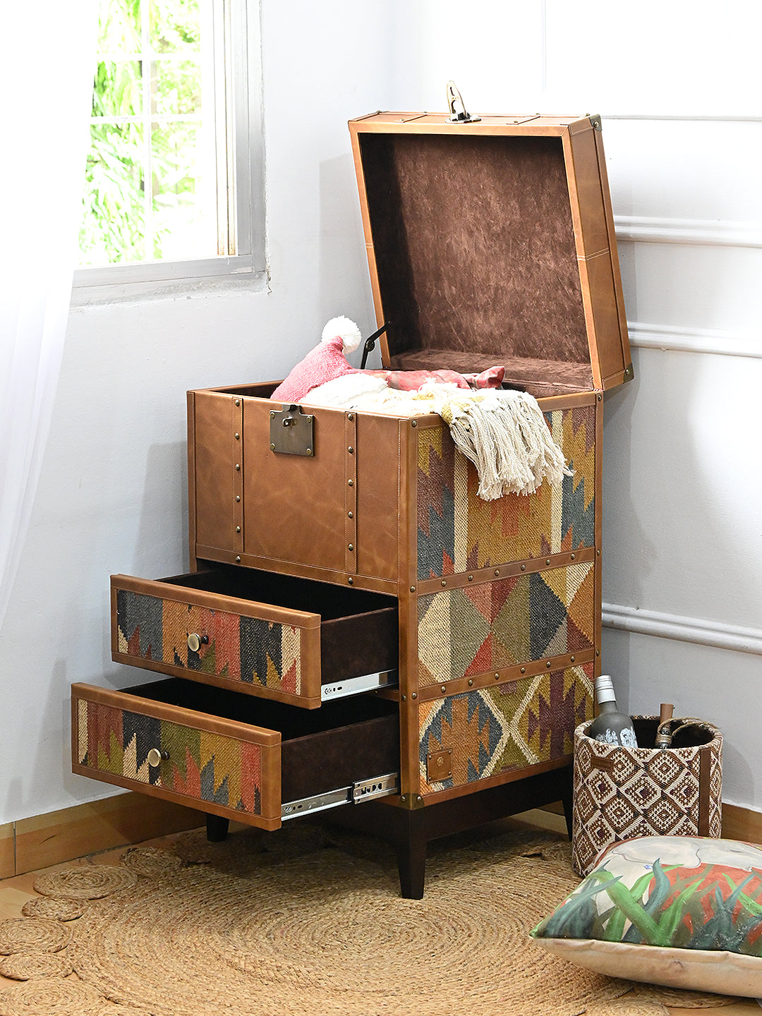 Osian trunk in a room setting with the lid open and a knitted throw spilling from the suede-lined void, drawers pulled out. Art Avenue, made to order.
