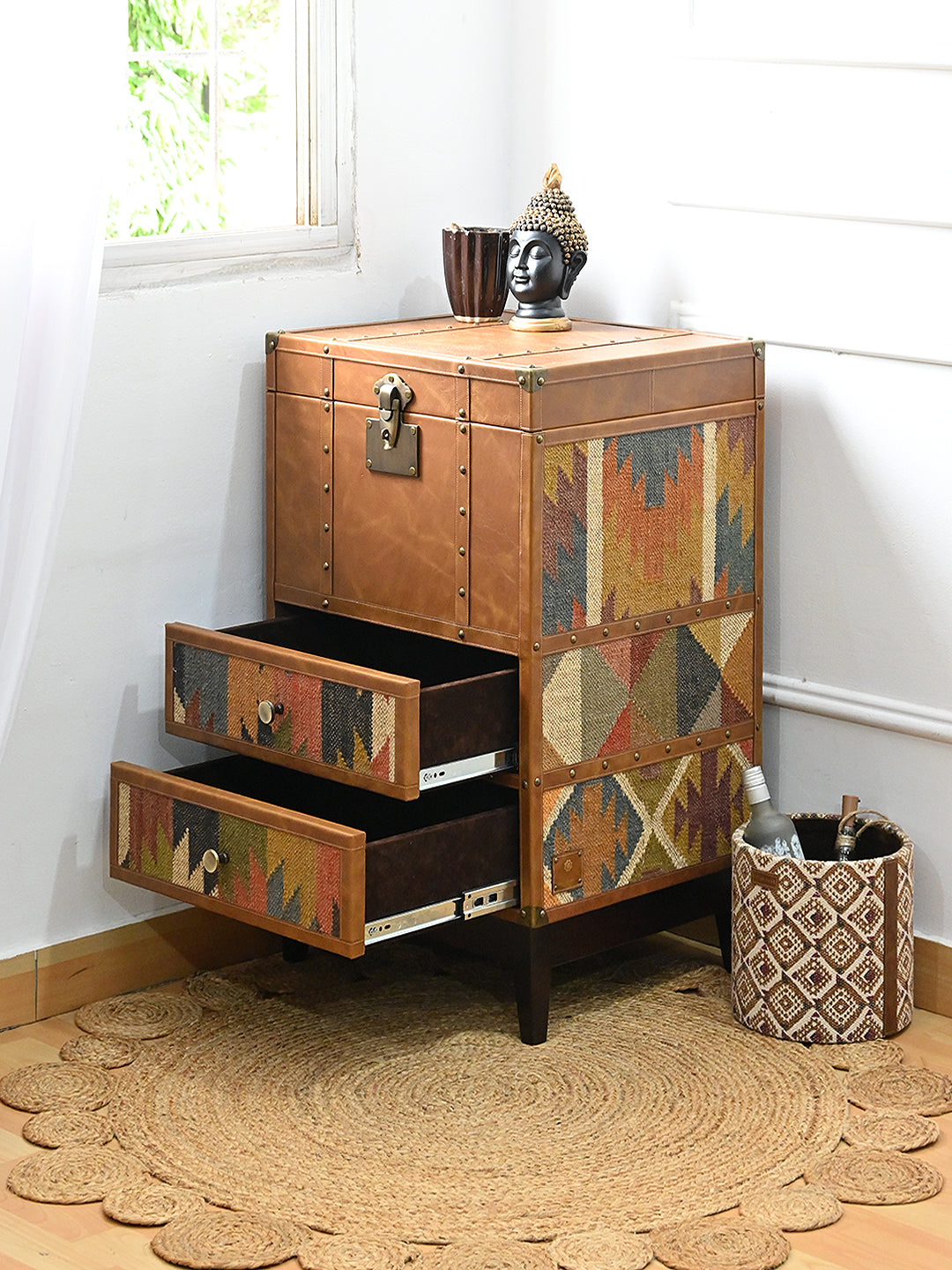 Osian trunk in a corner beside a woven basket, both kilim-fronted drawers extended. Art Avenue kilim and leather storage, made to order.