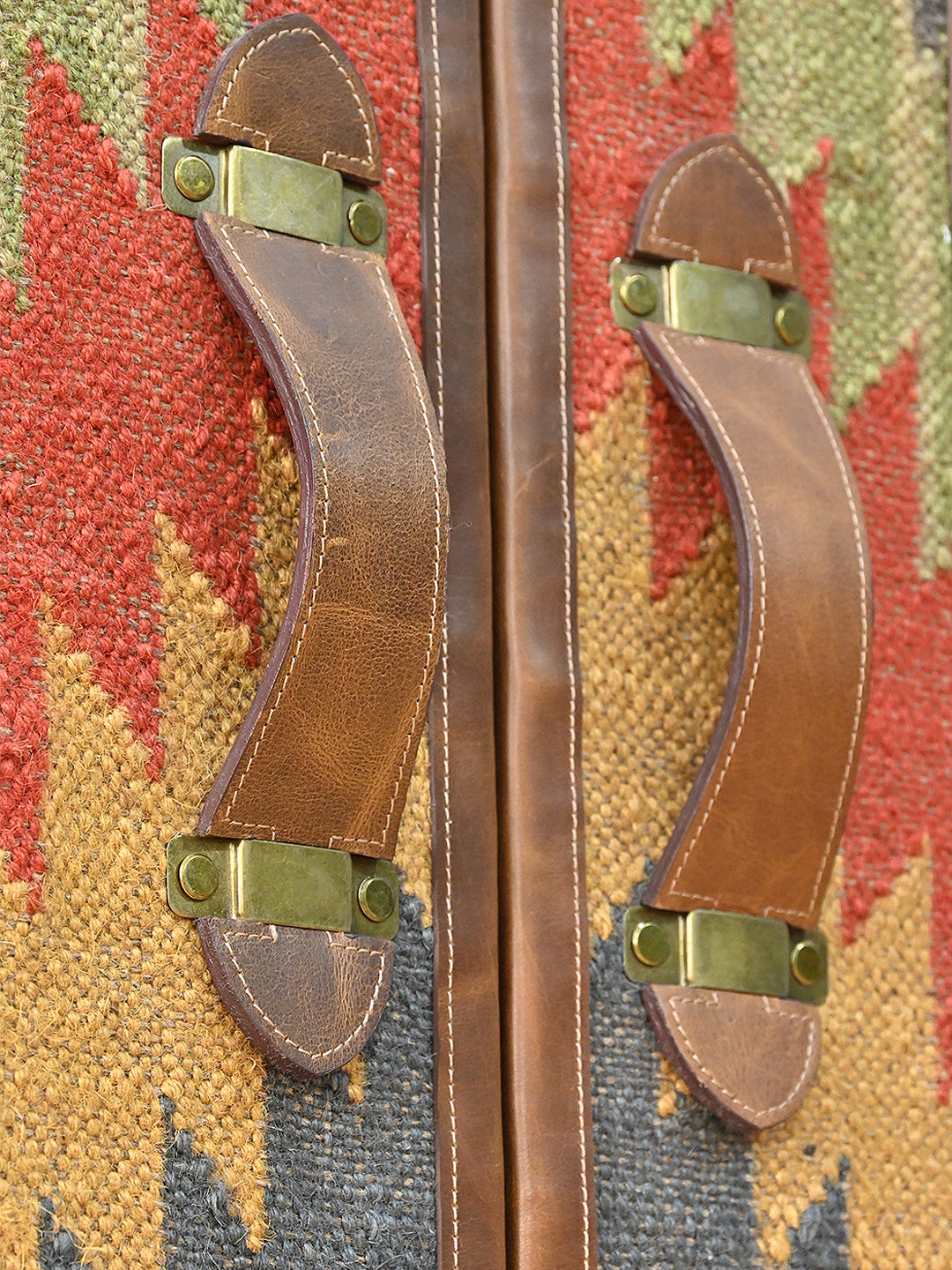 Detail of the curved leather strap pulls on brass plates against the kilim door panels — Art Avenue Shalimar cabinet