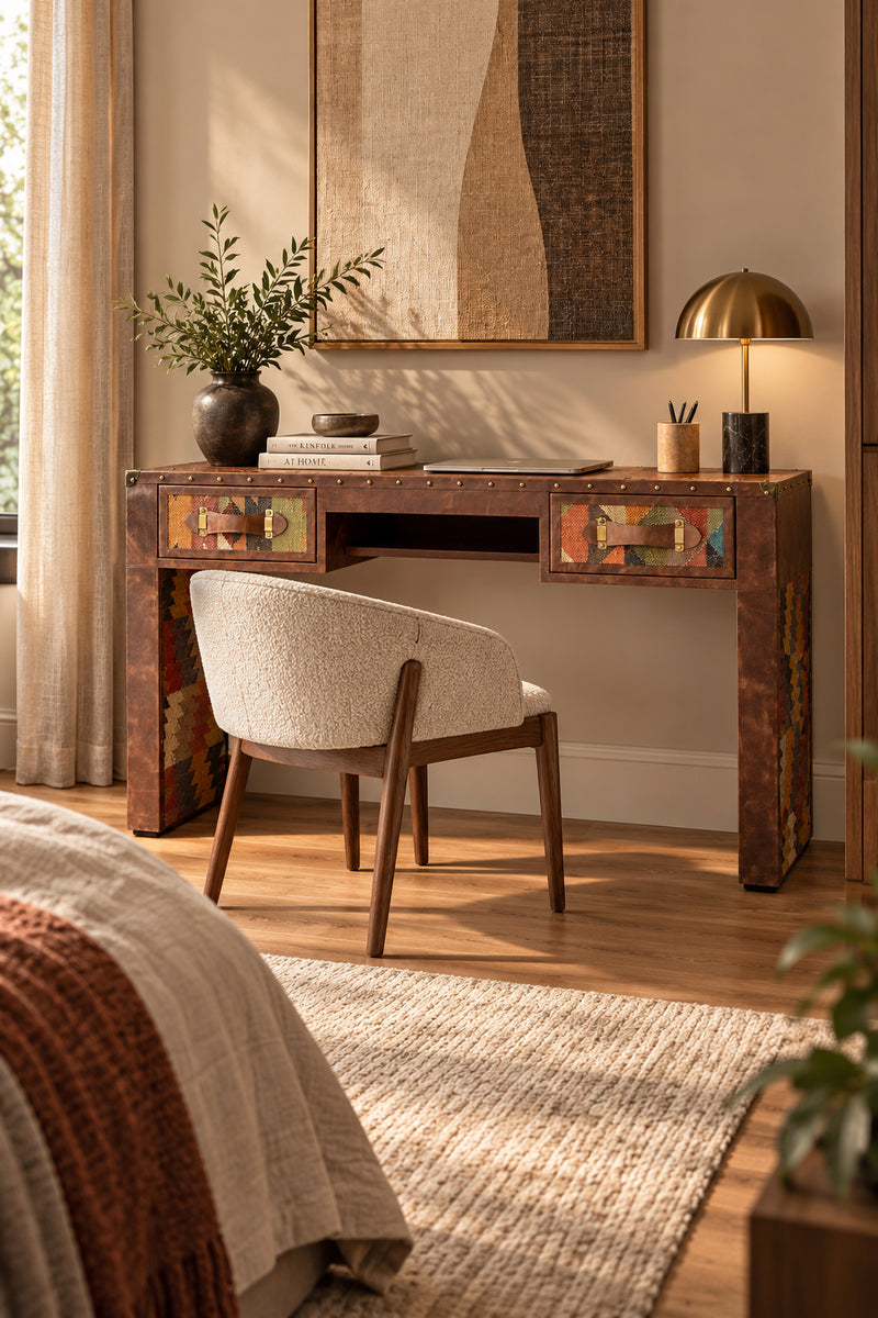 Dungarpur kilim and leather writing desk styled in a bedroom with an upholstered chair and table lamp